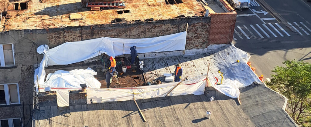 Workers putting up containment sheets for asbestos removal.